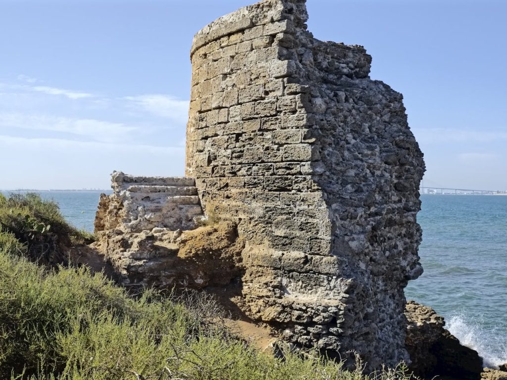 Explore the ancient coastal tower ruins in El Puerto de Santa María, Andalucía with a scenic sea backdrop.