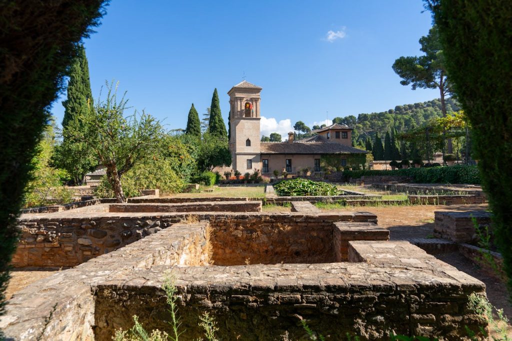 Explore the lush gardens of Alhambra under a bright summer sky, showcasing rich cultural heritage and Islamic architecture.